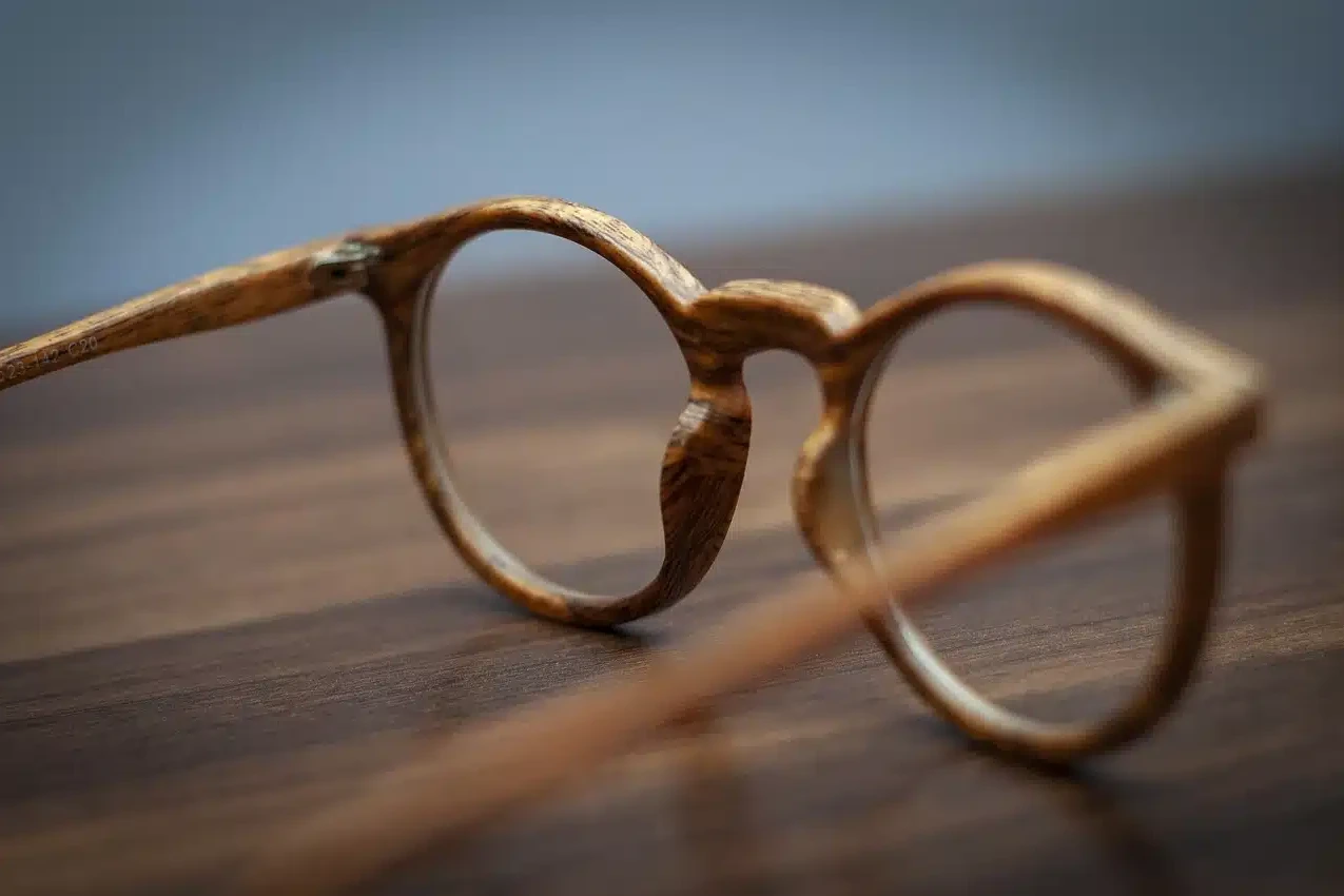paire de lunettes en bois posée sur une surface en bois, avec une mise au point sur la monture élégante et texturée.